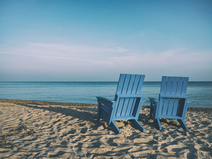Two Blue Adirondack Chairs on Sandy Beach Facing Ocean
