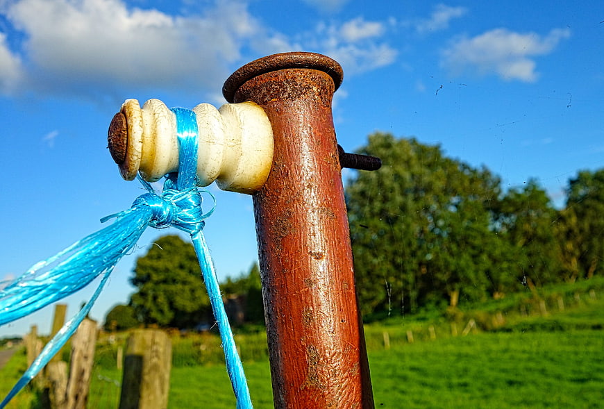 Close-up of vintage porcelain insulator on rusty fence post