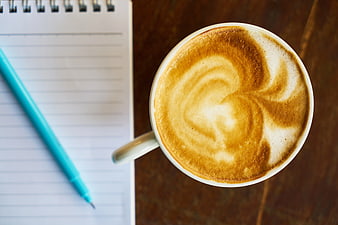 Top View Cappuccino with Latte Art Beside Notebook