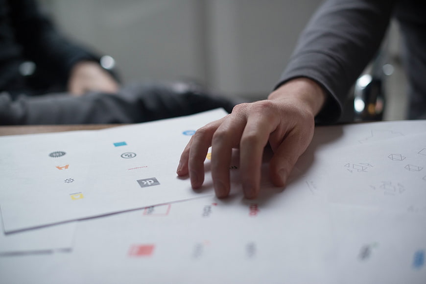 Hand selecting logo designs on paper