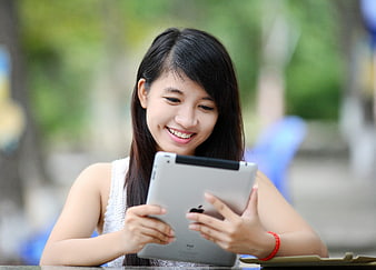 Happy Asian Woman Using Tablet Outdoors