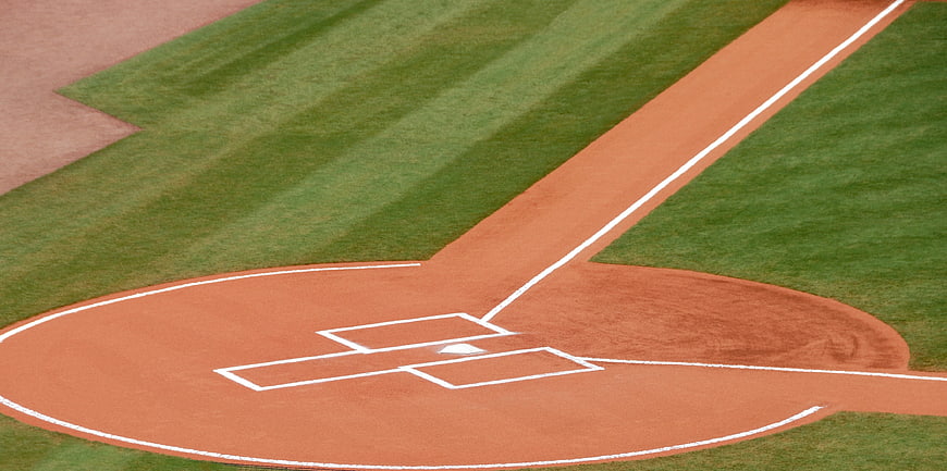 Empty baseball home plate and batter's box on a green field