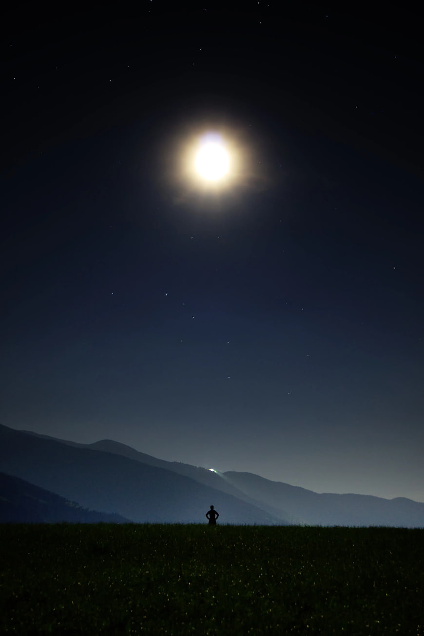 Silhouette of Person Standing in Field Under Bright Moon