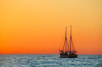 Silhouette of traditional sailing boat on ocean at sunset
