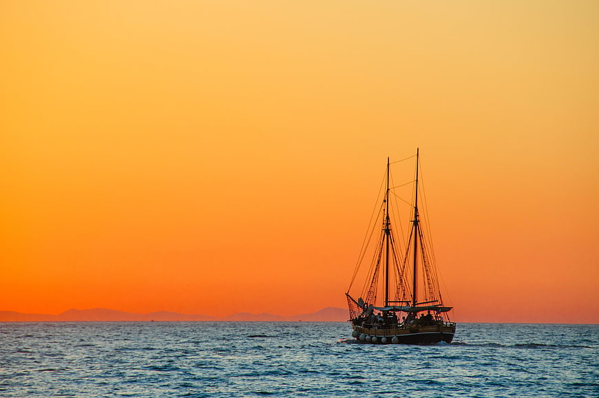 Silhouette of traditional sailing boat on ocean at sunset