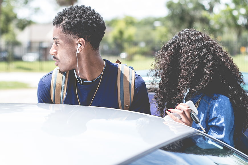 Young African American couple leaning on white car outdoors