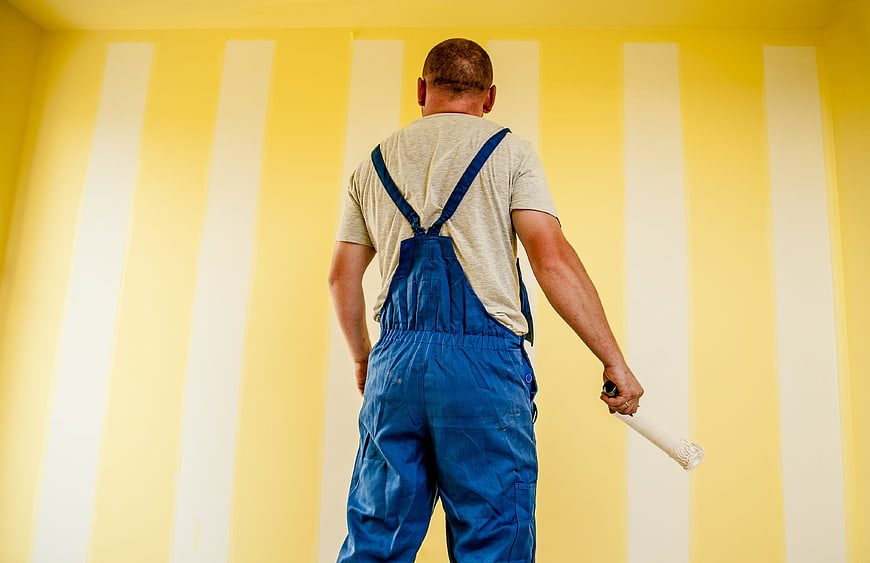 Painter in Blue Overalls Painting Yellow Striped Wall