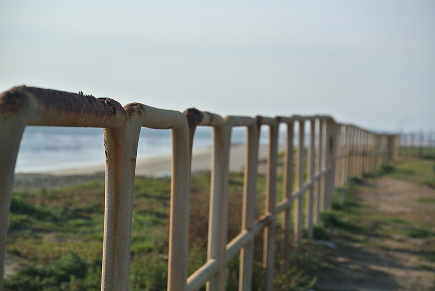 Rusty metal fence along a coastal path near the ocean
