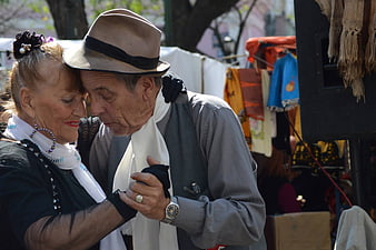 Senior couple embracing in traditional Argentine tango attire at outdoor market