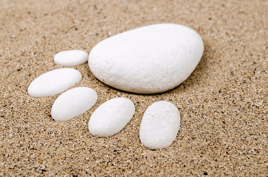 White stones arranged as footprint on sandy beach