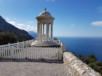 White marble temple overlooking the blue sea and mountains