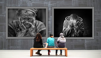 Three women viewing black and white portraits of despair in gallery