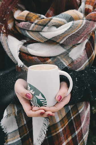 Woman holding Starbucks coffee mug in winter scarf