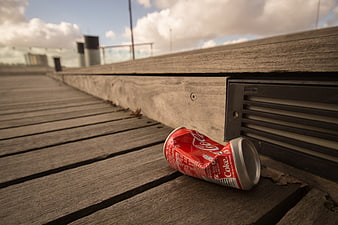 Crushed Coca-Cola can on wooden deck