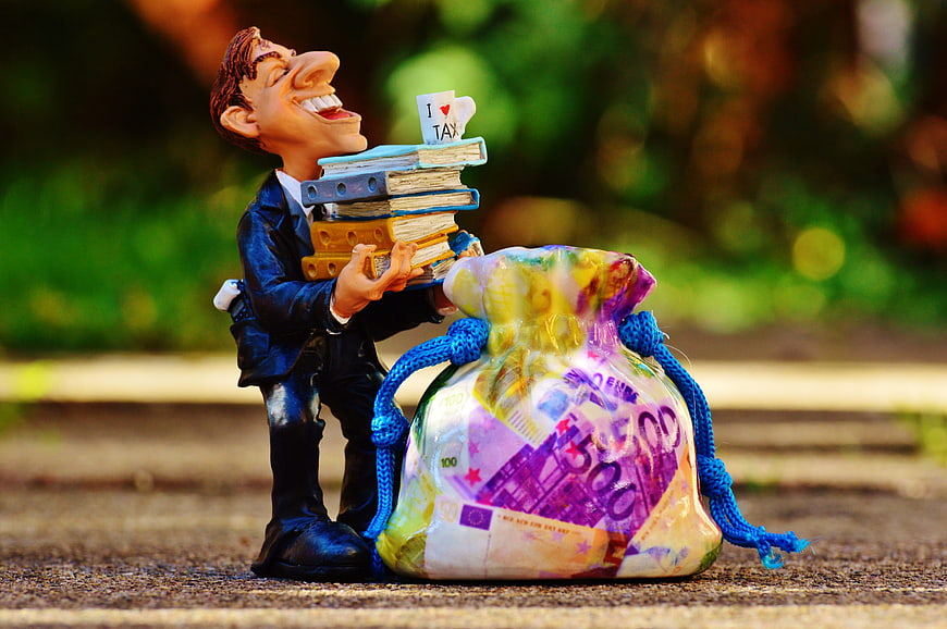 Businessman figurine holding tax forms and bag of euro banknotes