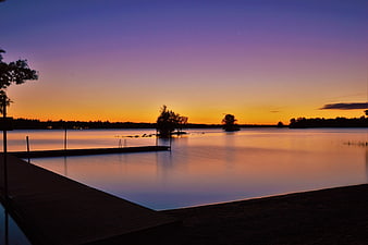 Serene Lake Sunset with Wooden Dock and Silhouetted Trees