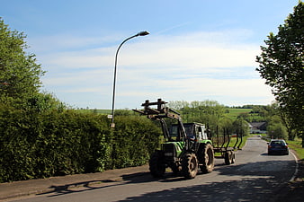 Green Tractor Transporting Timber on Rural Road