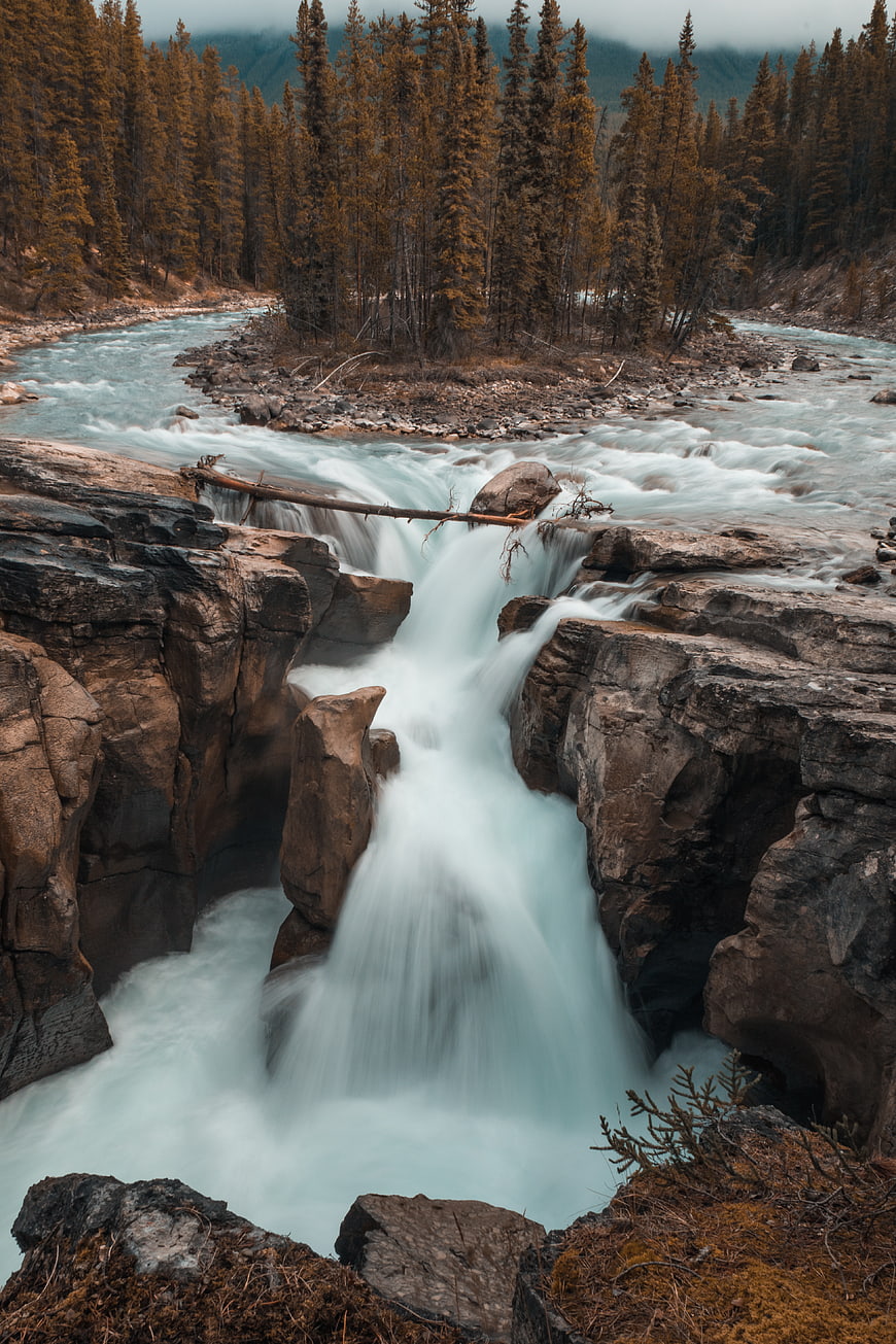 Majestic waterfall cascading through rocky gorge in autumn forest
