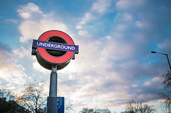 London Underground Sign Against Cloudy Sky