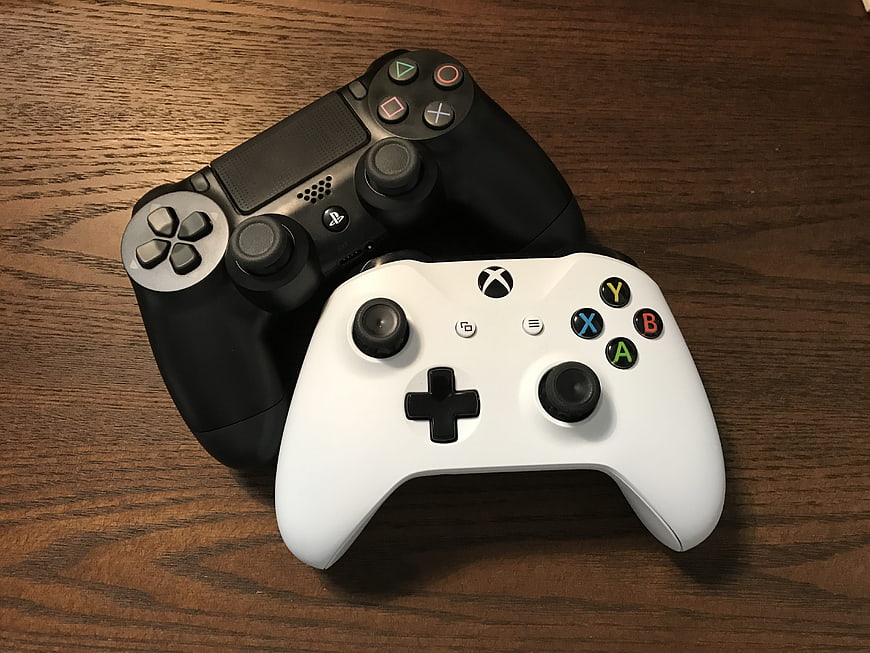 PlayStation and Xbox controllers on wooden table