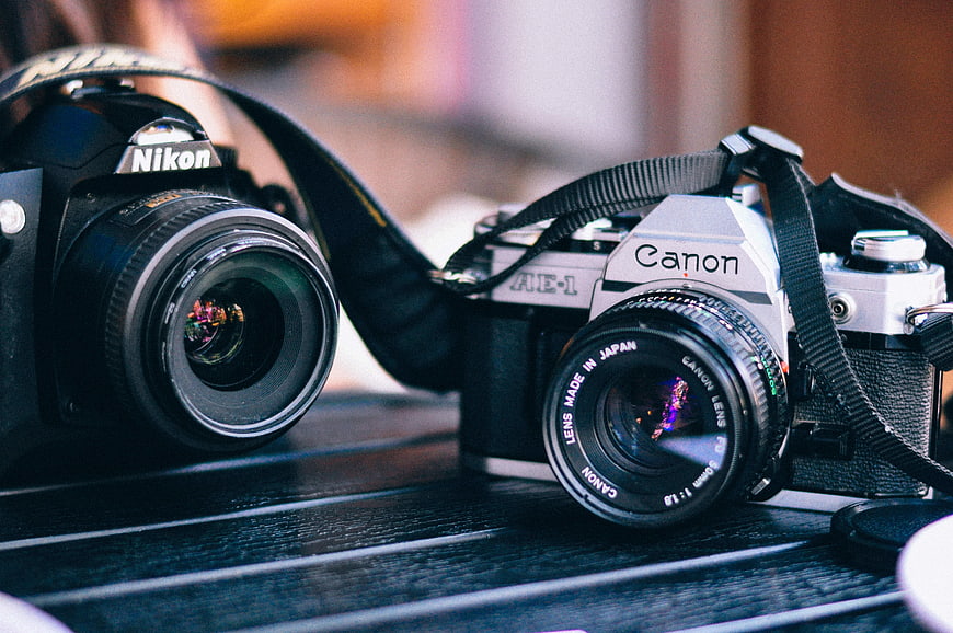 Vintage Canon AE-1 and Nikon Film Cameras on Wooden Table