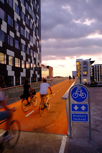 Cyclists on Orange Bike Path at Sunset in Modern City