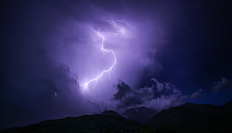 Dramatic purple lightning bolt striking over dark mountain silhouette