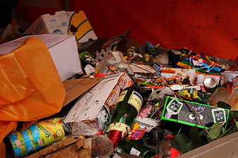 Close-up of mixed waste and discarded packaging in a red bin