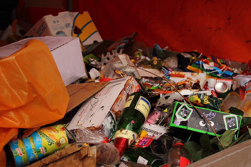 Close-up of mixed waste and discarded packaging in a red bin
