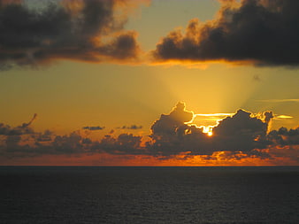 Dramatic Ocean Sunset with Golden Sun Rays Through Clouds