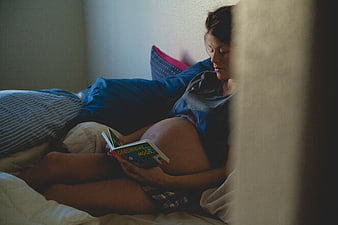 Pregnant woman reading Goodnight Moon in bed