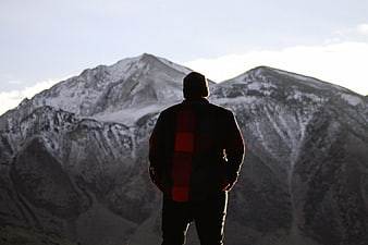 Man in Plaid Jacket Looking at Snowy Mountain Peaks