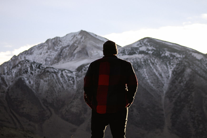 Man in Plaid Jacket Looking at Snowy Mountain Peaks