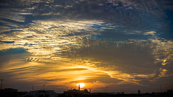 Dramatic golden sunset over city skyline with mosque silhouette