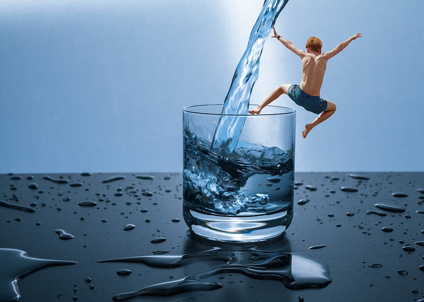 Man jumping into a glass of water with splash