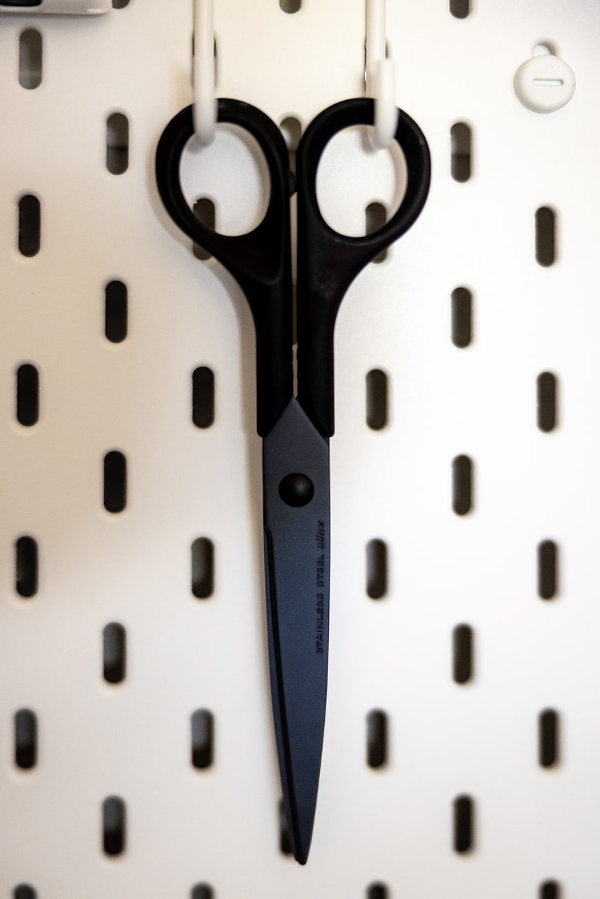 Black Scissors Hanging on White Pegboard
