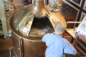 Brewer Inspecting Copper Kettle During Craft Beer Brewing Process