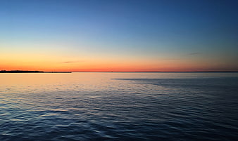 Serene Sunset Over Calm Ocean with Orange and Blue Sky