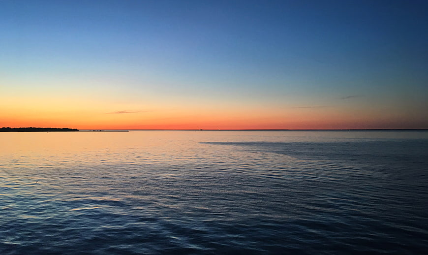Serene Sunset Over Calm Ocean with Orange and Blue Sky