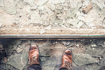 First-person view of brown leather boots standing on broken glass shards
