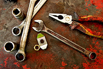 Rusty wrenches and pliers on a worn red metal workbench