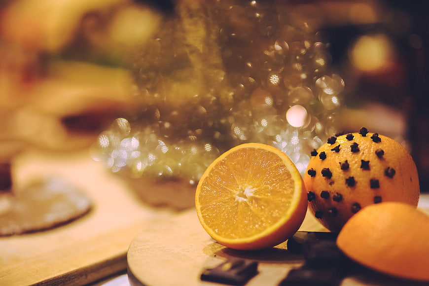 Sliced orange and spiced orange with cloves on wooden board