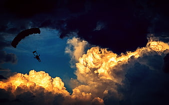 Silhouette of Parachutist Against Dramatic Sunset Clouds