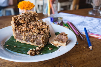 Slice of crumble cake on banana leaf with colored pencils