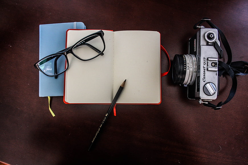 Vintage Camera, Notebook, and Glasses on Wooden Desk