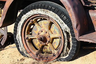 Rusty Vintage Truck Wheel With Torn Tire On Sand