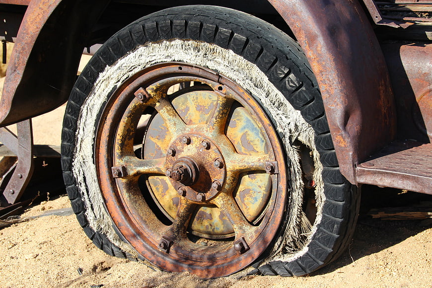 Rusty Vintage Truck Wheel With Torn Tire On Sand