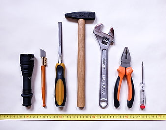 Flat lay of assorted hand tools and measuring tape on white background
