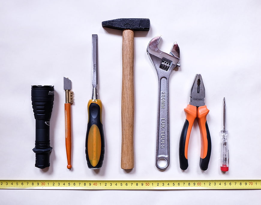 Flat lay of assorted hand tools and measuring tape on white background