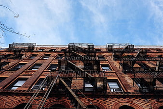 Low angle view of red brick building with black fire escapes